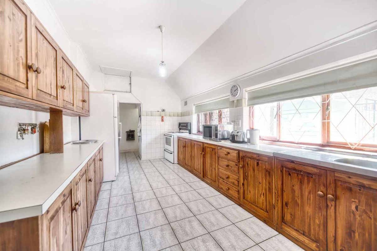 A functional kitchen featuring extensive wooden cabinetry, tiled flooring, a built-in oven, and ample counter space with a double sink.