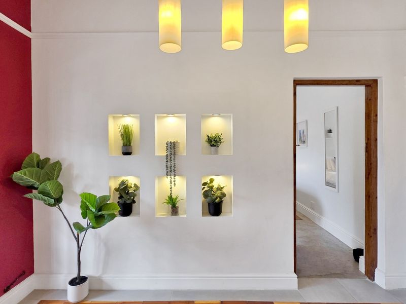 A bright living area featuring a feature wall with illuminated recessed niches, modern pendant lighting, and clean architectural finishes.
