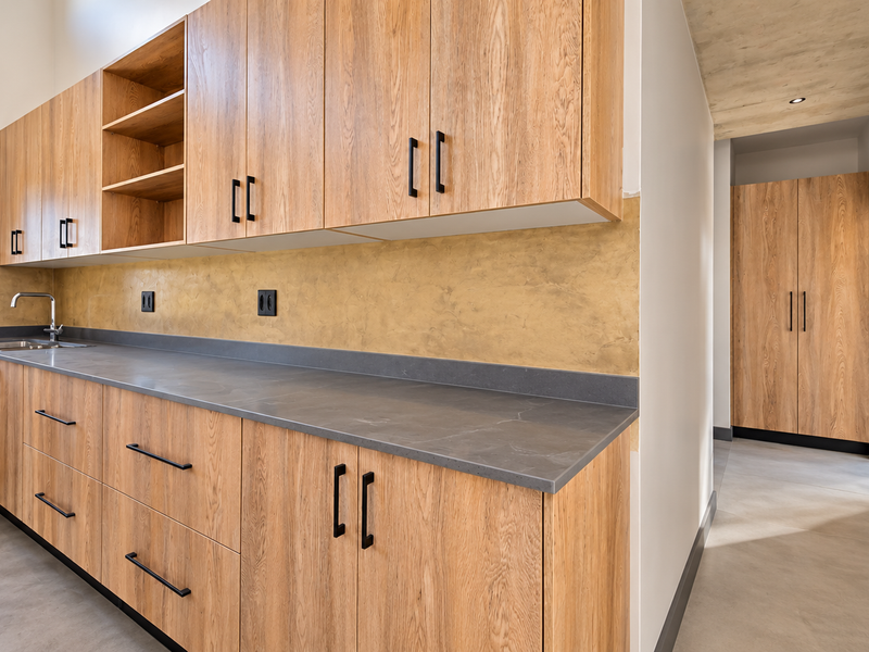 Modern kitchen featuring wood-grain cabinetry, stone countertops, and a textured backsplash, complemented by sleek hardware and recessed lighting.