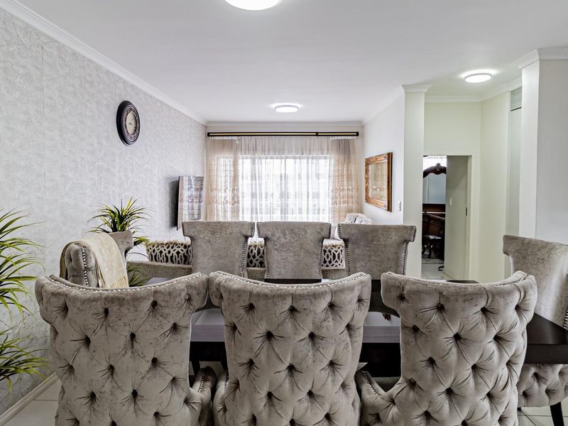 An open-plan living and dining area featuring tiled floors, textured wallpaper, and a modern kitchen with stone countertops and recessed lighting.