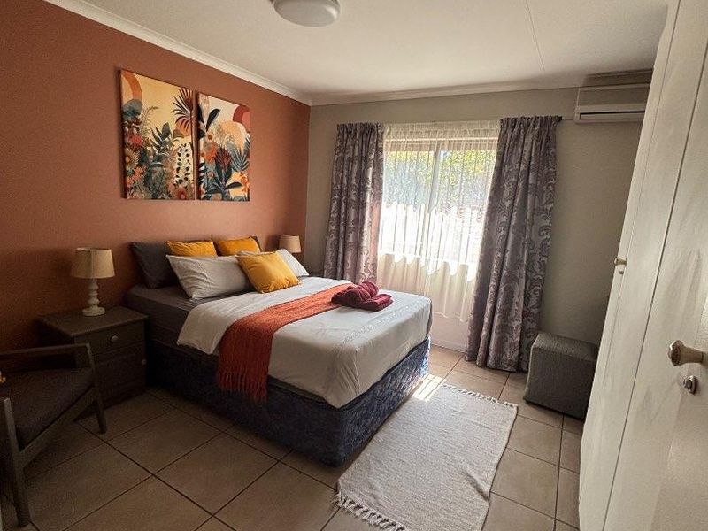 A bedroom featuring tiled flooring, a built-in wardrobe, and a wall-mounted air conditioning unit.