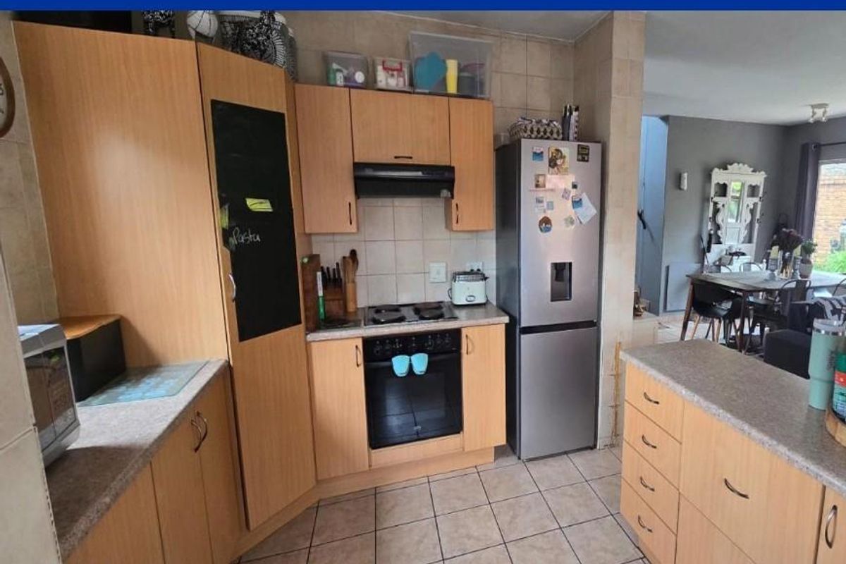 A functional kitchen featuring light wood cabinetry, tiled backsplash, built-in oven, hob, and extractor fan, flowing into an adjacent dining area.