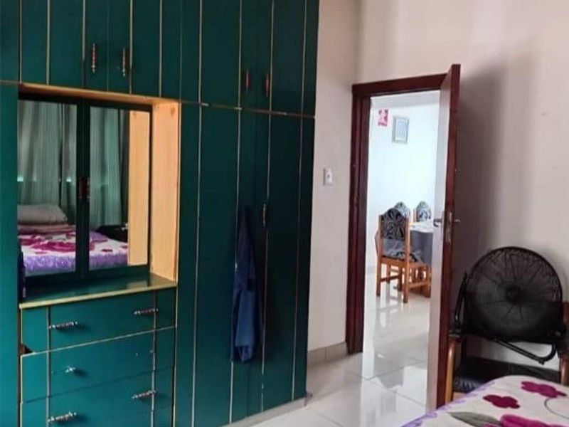 Bedroom featuring built-in dark green cabinetry with integrated vanity and tiled flooring, providing functional storage space.