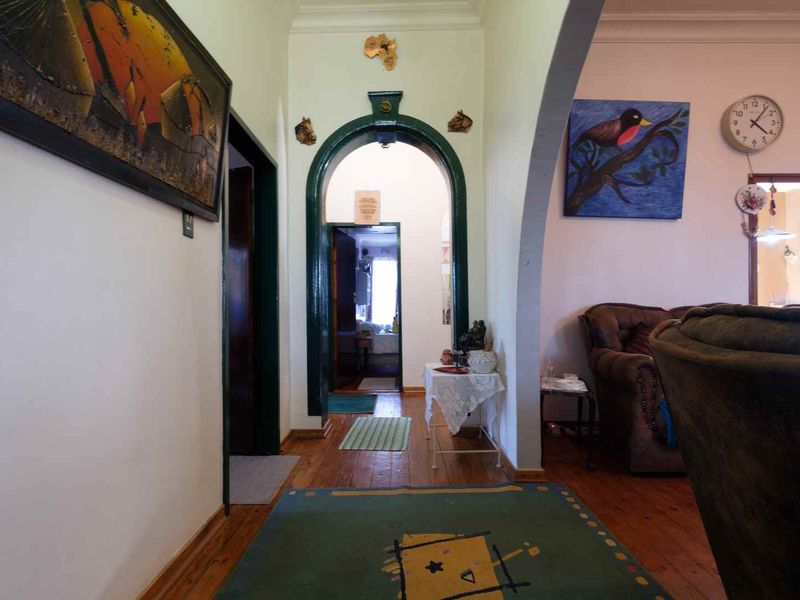 A hallway featuring a distinctive arched doorway, hardwood flooring, and traditional cornice detailing, providing access to adjacent living spaces.