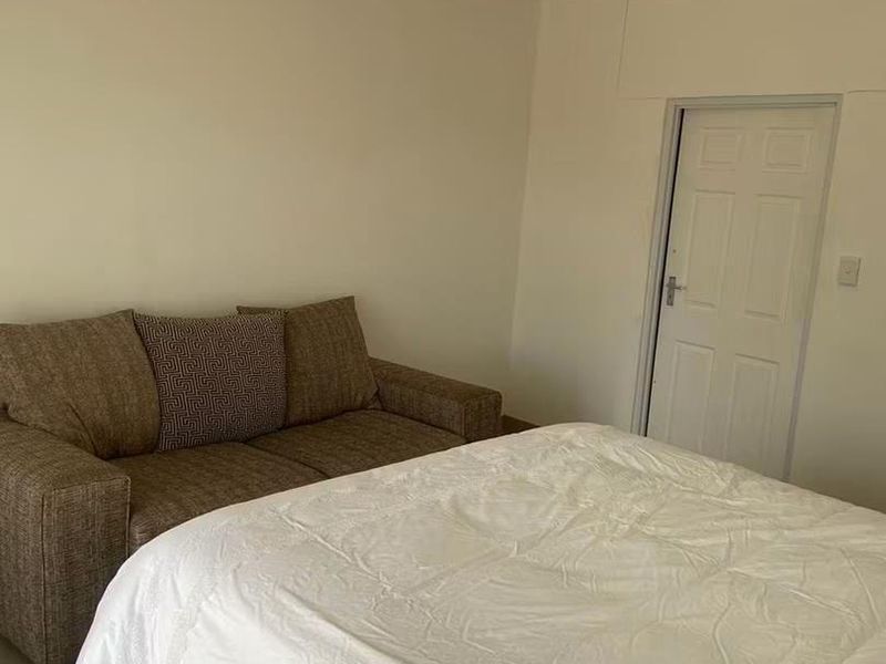 A simple bedroom featuring neutral walls, tiled flooring, and a standard interior door.