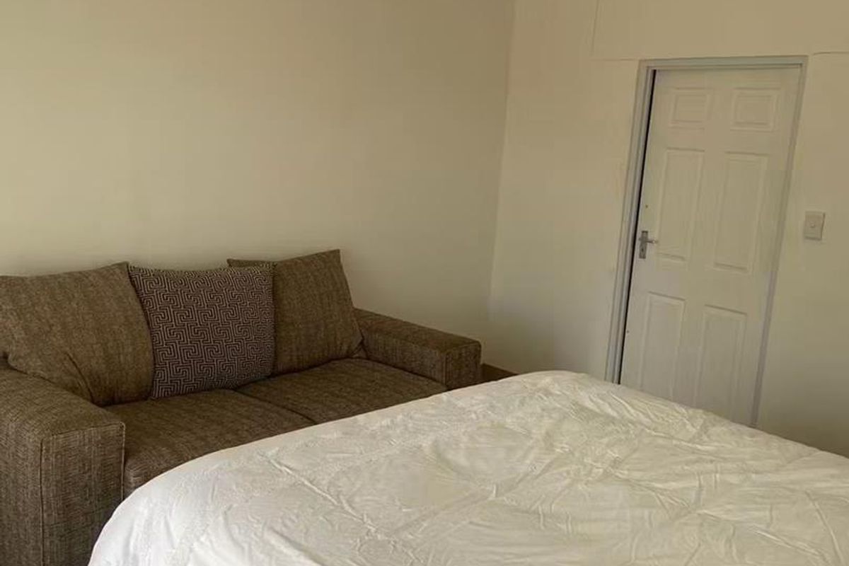 A simple bedroom featuring neutral walls, tiled flooring, and a standard interior door.