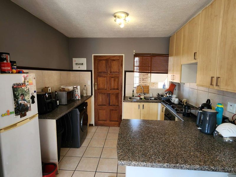A functional kitchen featuring light wood cabinetry, granite countertops, tiled flooring, and a tiled backsplash, providing a practical workspace with integrated sink and hob.