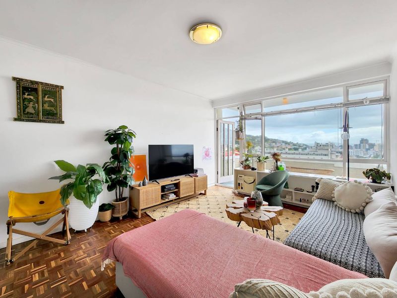 A bright living room featuring original parquet flooring and expansive windows that provide natural light and urban views.