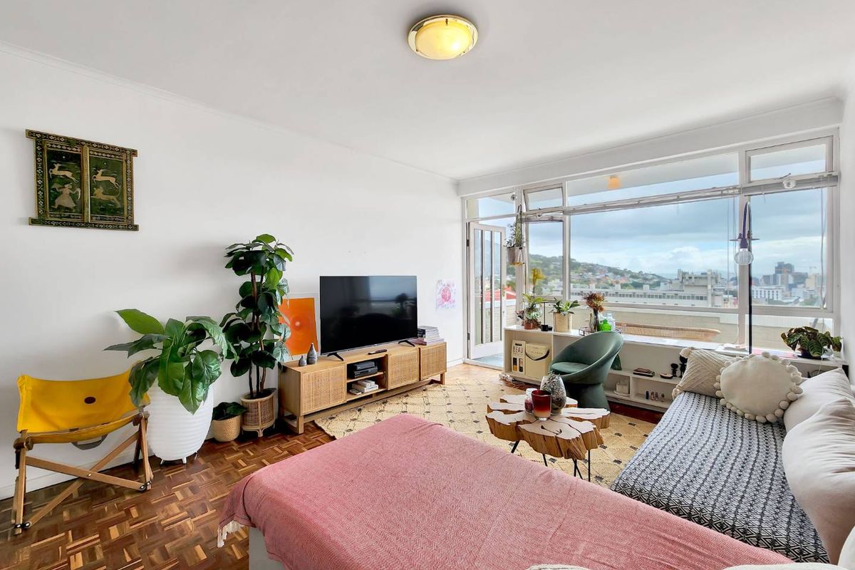 A bright living room featuring original parquet flooring and expansive windows that provide natural light and urban views.