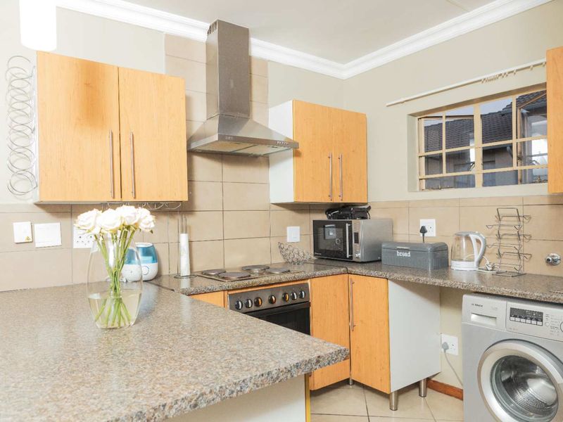 Functional kitchen featuring laminate cabinetry, granite countertops, built-in oven, electric hob, stainless steel extractor fan, and space for a washing machine.