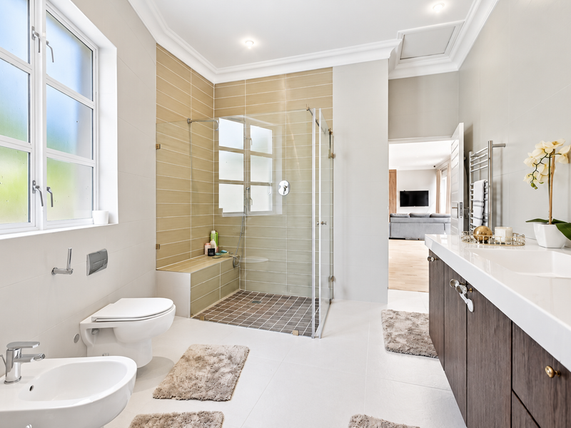 Modern bathroom featuring a walk-in shower with glass screen, wall-mounted toilet, bidet, and a sleek vanity cabinet with integrated sink.