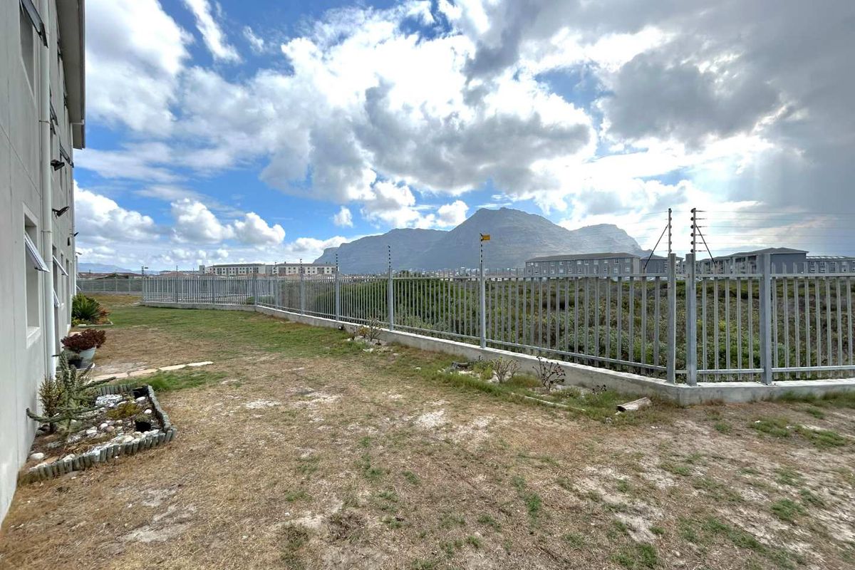 A view of the rear exterior area featuring a perimeter fence with electric security wiring and mountain views in the background.