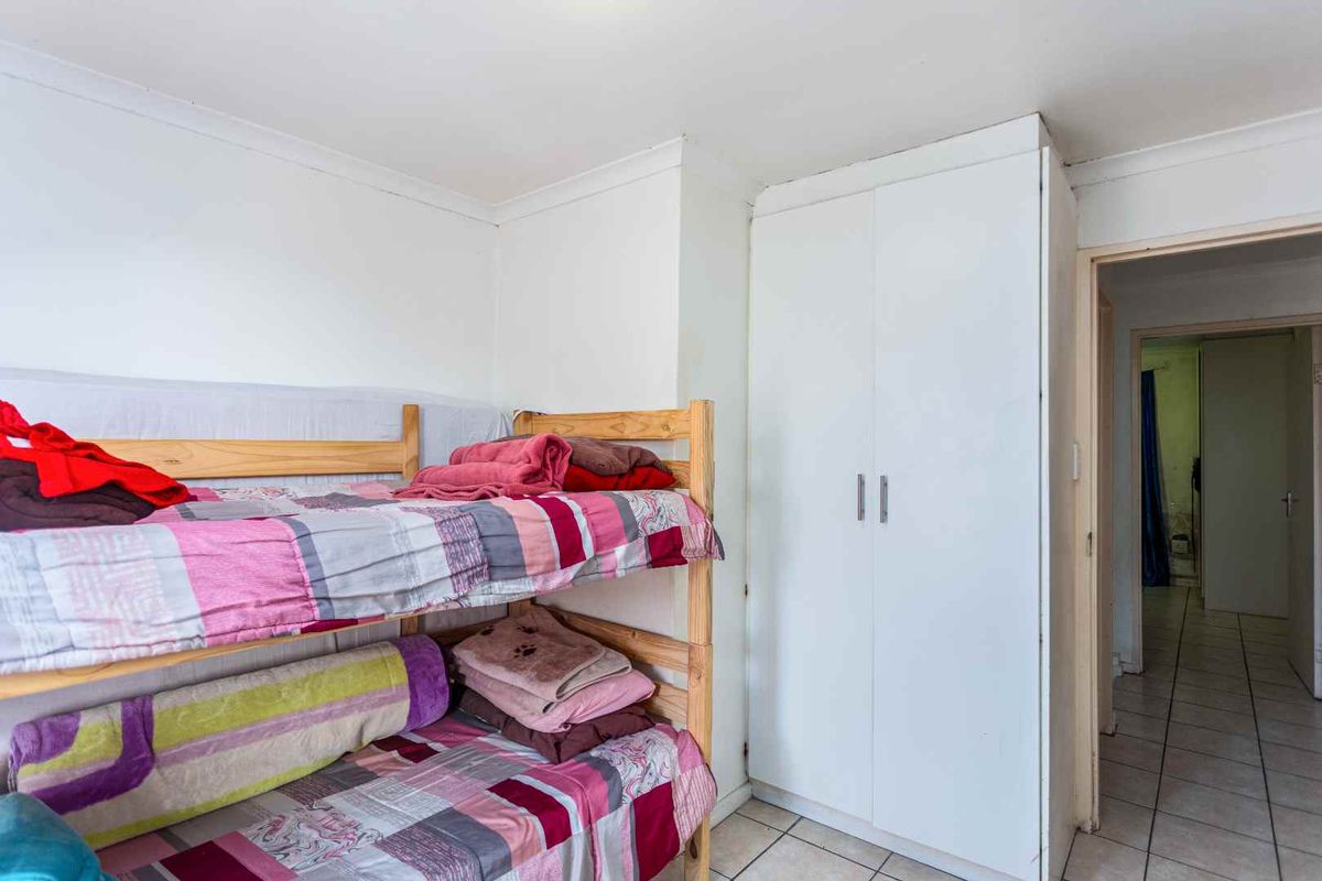 A bedroom featuring built-in white cabinetry and tiled flooring, providing functional storage space within the apartment.