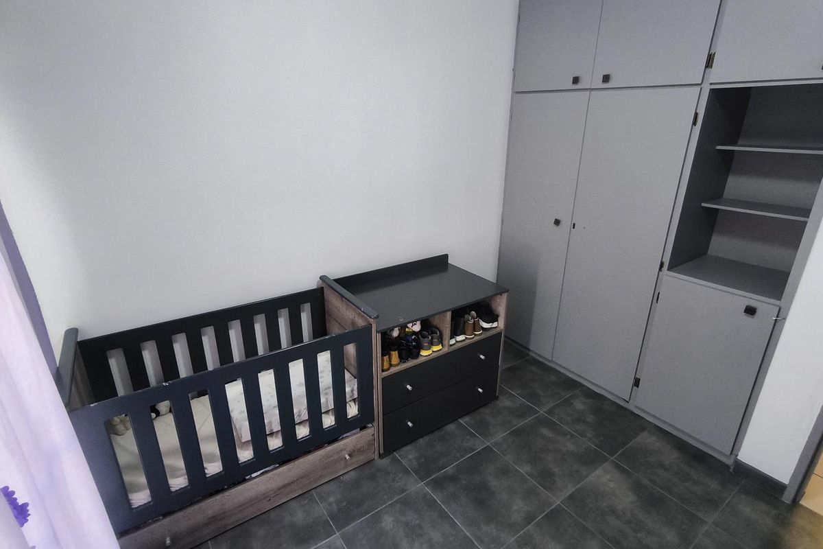 A bedroom featuring grey built-in cupboards and dark tiled flooring, providing functional storage space.