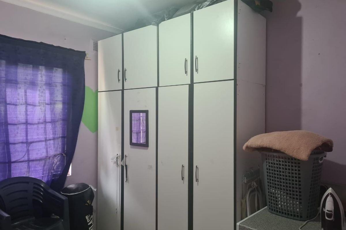 A bedroom featuring built-in white cupboards with dark trim and decorative cornice detailing.