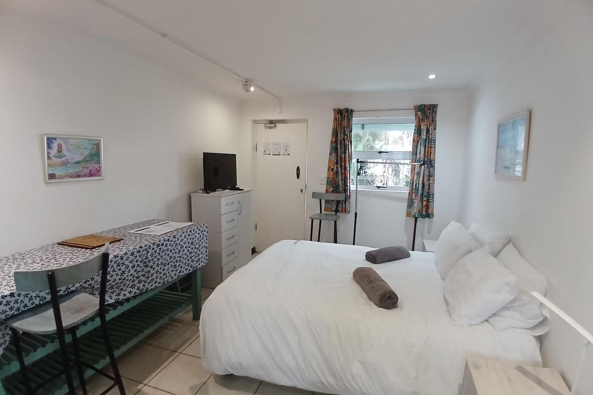 A functional bedroom featuring tiled flooring, a window with curtains, and a standard entry door.