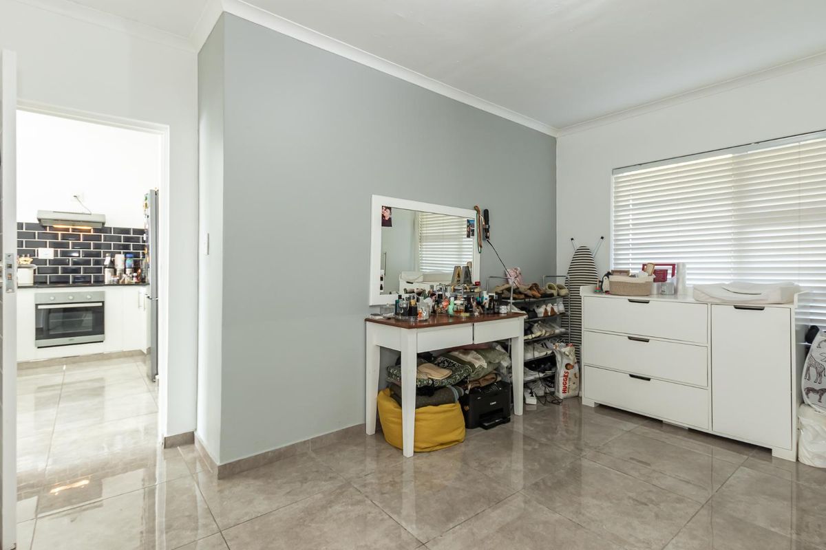 A bedroom featuring tiled flooring and a view into the adjacent kitchen with built-in oven and hob.