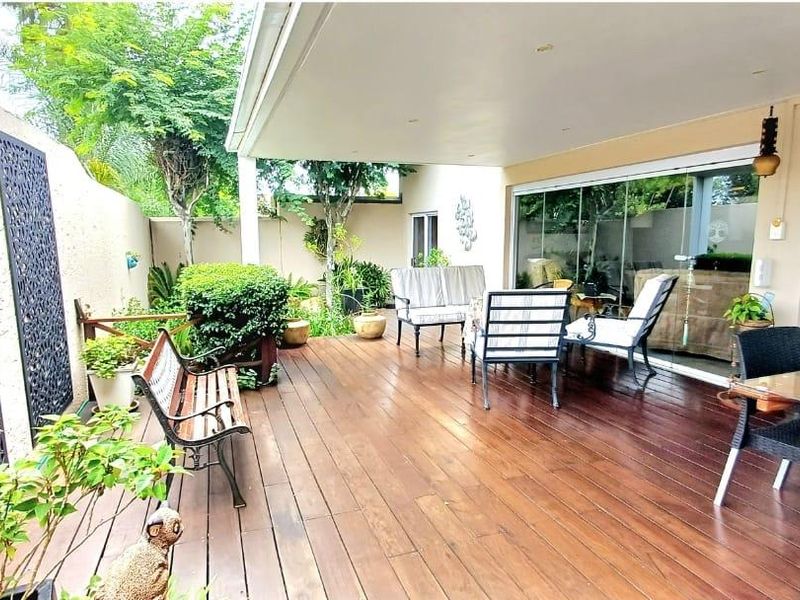 A well-maintained covered patio featuring wooden decking, recessed lighting, and large sliding glass doors that provide seamless access to the interior living space.