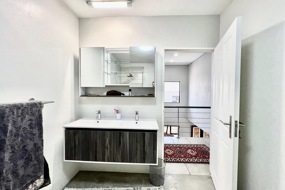 A modern bathroom featuring a double vanity with a dark wood-finish cabinet, integrated sinks, and a mirrored medicine cabinet.