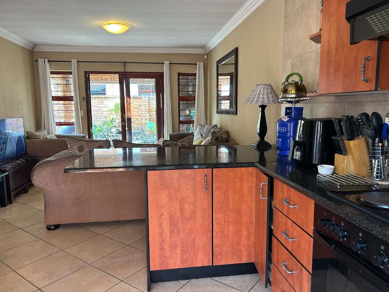 Open-plan kitchen and living area featuring granite countertops, built-in cabinetry, and sliding glass doors leading to an outdoor patio space.