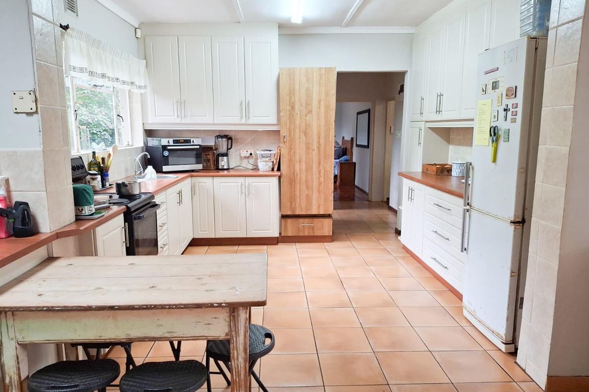 A functional kitchen featuring white cabinetry, tiled flooring, and ample counter space, providing a practical layout for daily meal preparation.