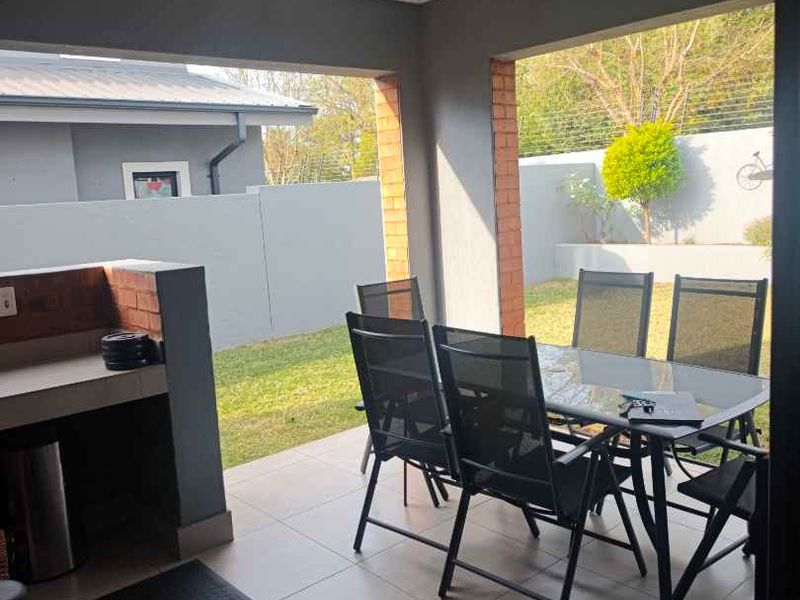 Covered patio area featuring a built-in braai, tiled flooring, and recessed lighting, overlooking the rear garden.