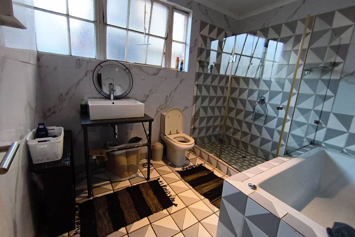 Modernized bathroom featuring a vessel sink, glass-enclosed shower, and a built-in bathtub with geometric patterned wall and floor tiles.