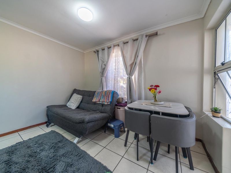 A compact living area featuring tiled flooring and large windows, providing a functional space for relaxation and dining.