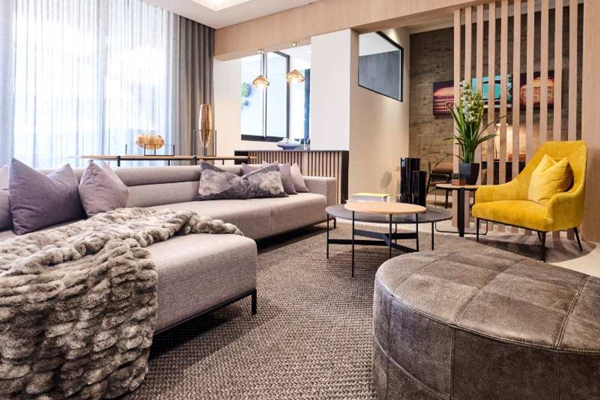 Modern open-plan living area featuring recessed ceiling lighting, timber-look wall paneling, and decorative timber slat room dividers.