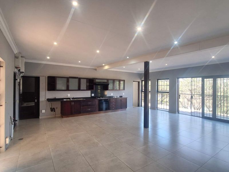 Spacious open-plan living area featuring a modern kitchen with built-in cabinetry, tiled floors, and large sliding doors leading to an outdoor space.