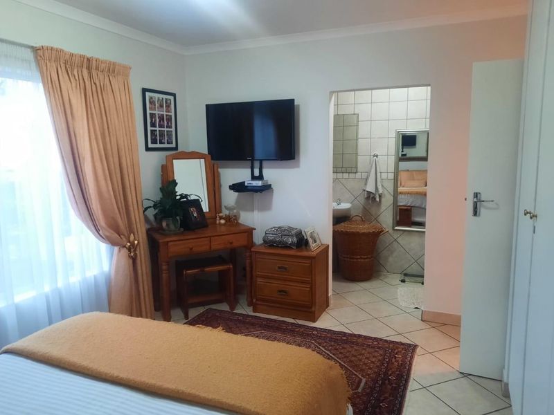 A bedroom featuring tiled flooring and an adjoining en-suite bathroom, offering a functional layout with neutral wall finishes.