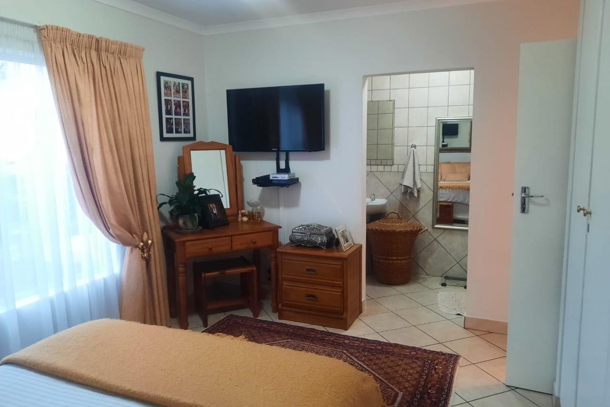 A bedroom featuring tiled flooring and an adjoining en-suite bathroom, offering a functional layout with neutral wall finishes.