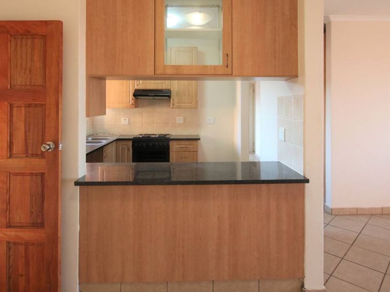 A functional kitchen featuring light wood cabinetry, granite countertops, a breakfast bar, and tiled flooring, offering a clean and practical layout.