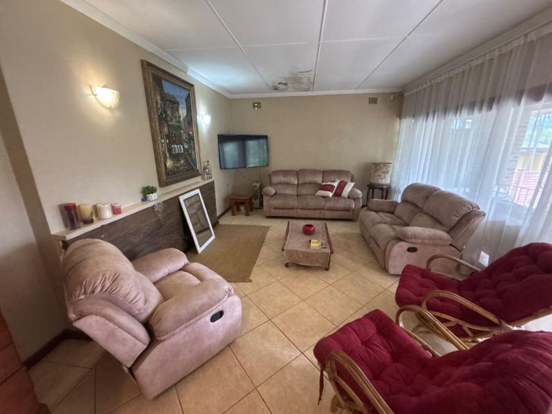A living room featuring tiled flooring and wall sconces, currently showing visible water damage on the ceiling.