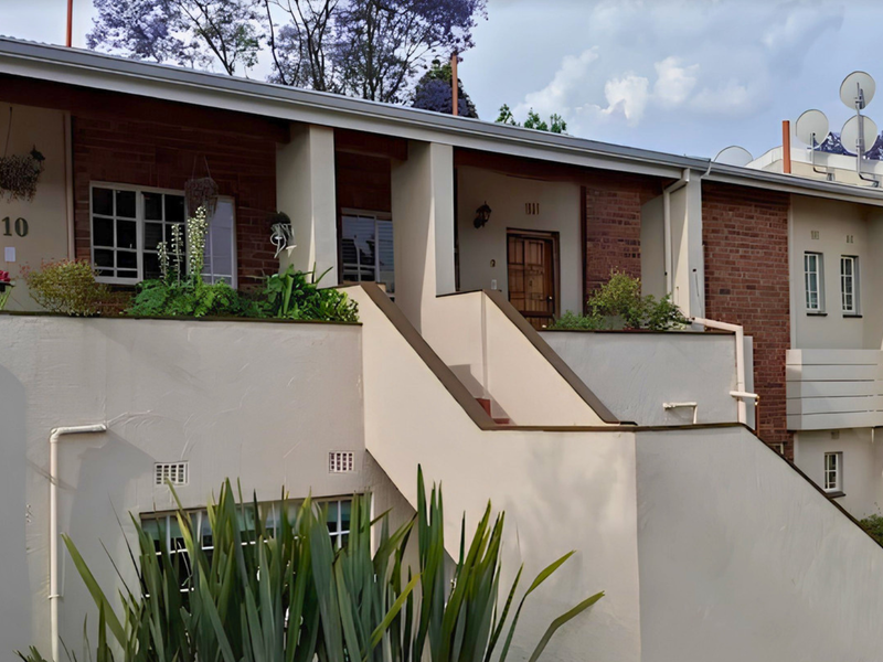 Exterior view of a multi-level apartment complex featuring brick and rendered facade, external staircases, and private balcony access.