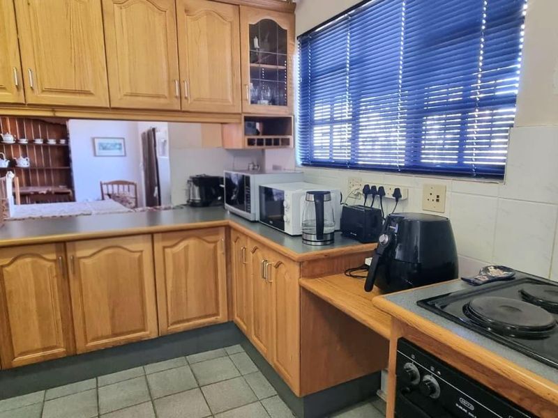 A functional kitchen featuring traditional wooden cabinetry, tiled backsplash, and built-in cooking appliances, offering a classic layout with potential for modern updates.