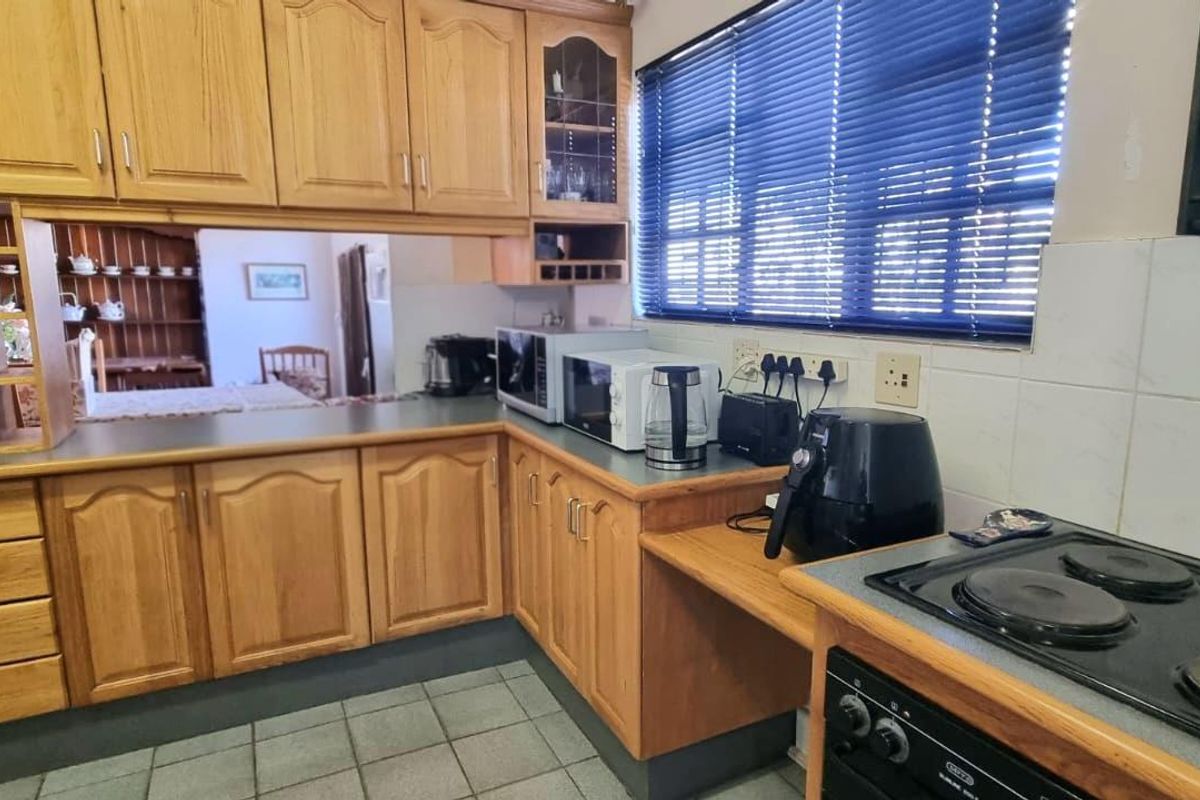A functional kitchen featuring traditional wooden cabinetry, tiled backsplash, and built-in cooking appliances, offering a classic layout with potential for modern updates.