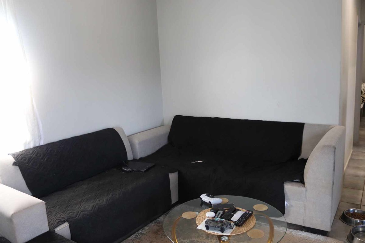 A living room area featuring neutral wall finishes and tiled flooring, providing a functional space for relaxation.