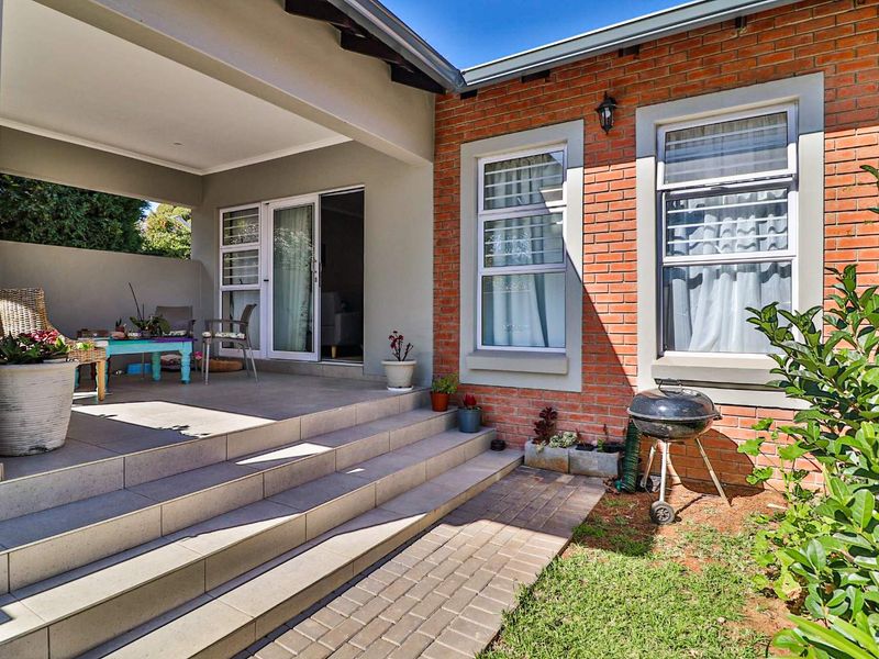 A covered patio area featuring tiled flooring, brick exterior walls, and sliding door access to the interior living space.