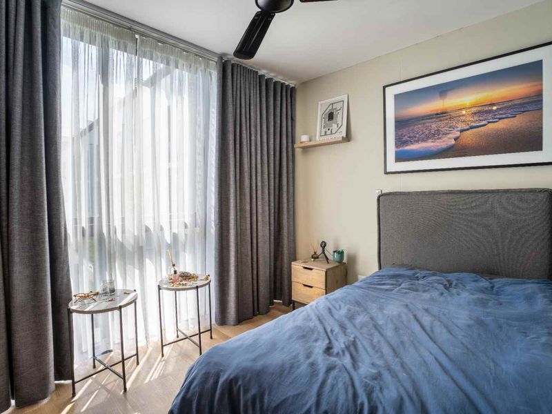 A well-maintained bedroom featuring a ceiling fan, built-in wardrobe, and large sliding glass doors that provide ample natural light.