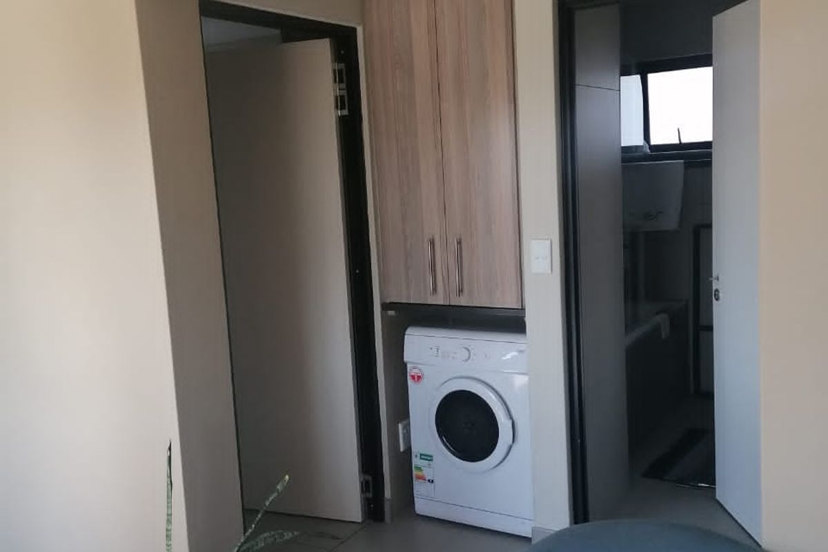 A functional laundry nook featuring built-in cabinetry and tiled flooring, conveniently positioned between internal doorways.