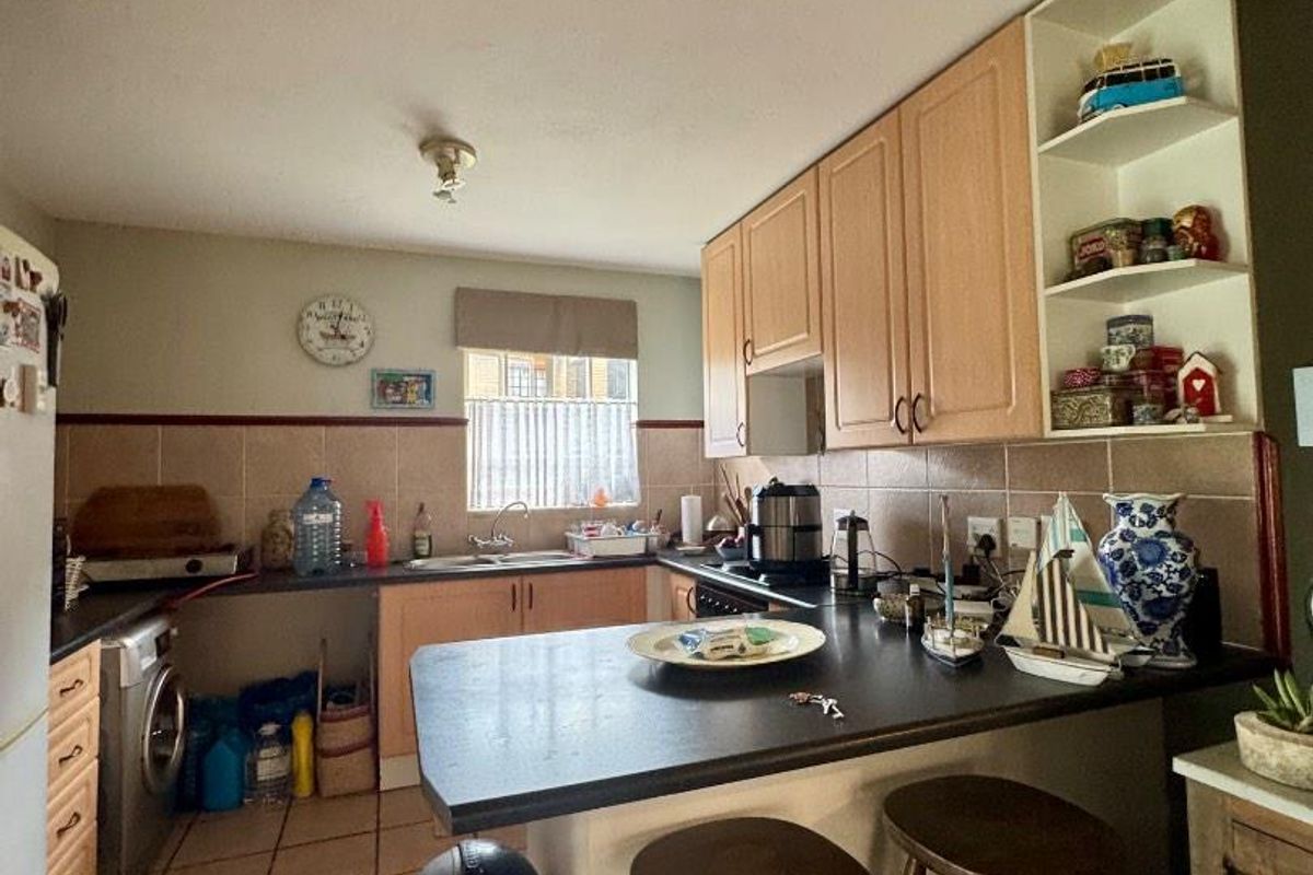 A functional kitchen featuring laminate cabinetry, tiled backsplash, and a built-in breakfast bar with integrated sink and extractor fan.