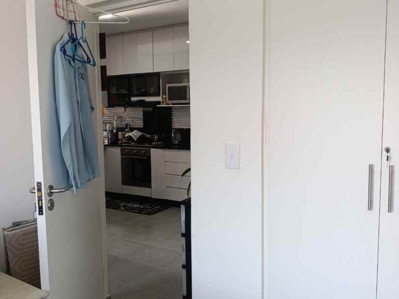 A view from a hallway looking into a kitchen area, featuring tiled flooring and a built-in cupboard.