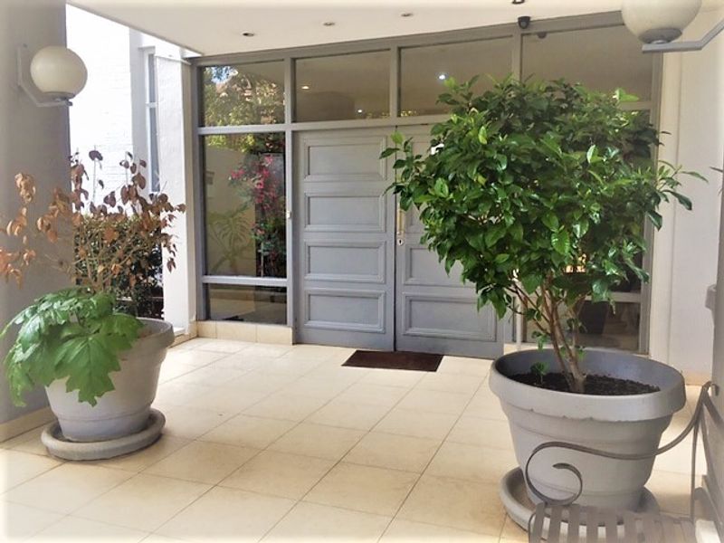 A covered entrance area featuring tiled flooring, double doors with glass paneling, and integrated ceiling lighting.