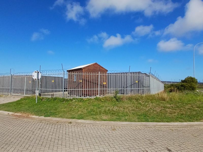 Industrial property exterior featuring secure perimeter fencing with razor wire and electric security measures, situated on a paved corner lot.