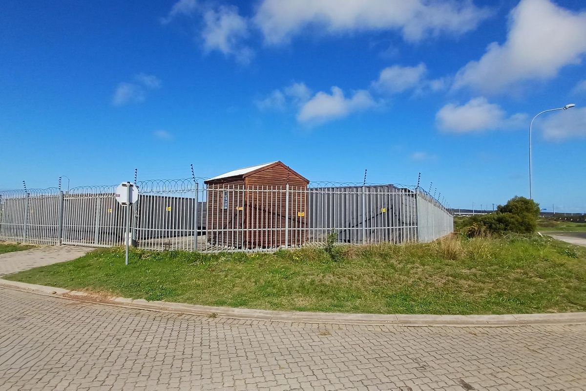 Industrial property exterior featuring secure perimeter fencing with razor wire and electric security measures, situated on a paved corner lot.