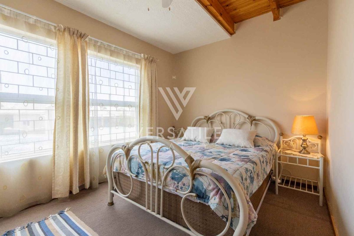 A bedroom featuring exposed timber ceiling beams, carpeted flooring, and security bars on the windows.