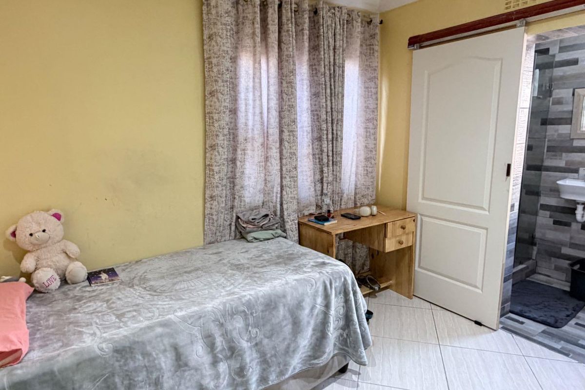 A bedroom featuring tiled flooring and direct access to an en-suite bathroom, providing a functional layout with neutral finishes.