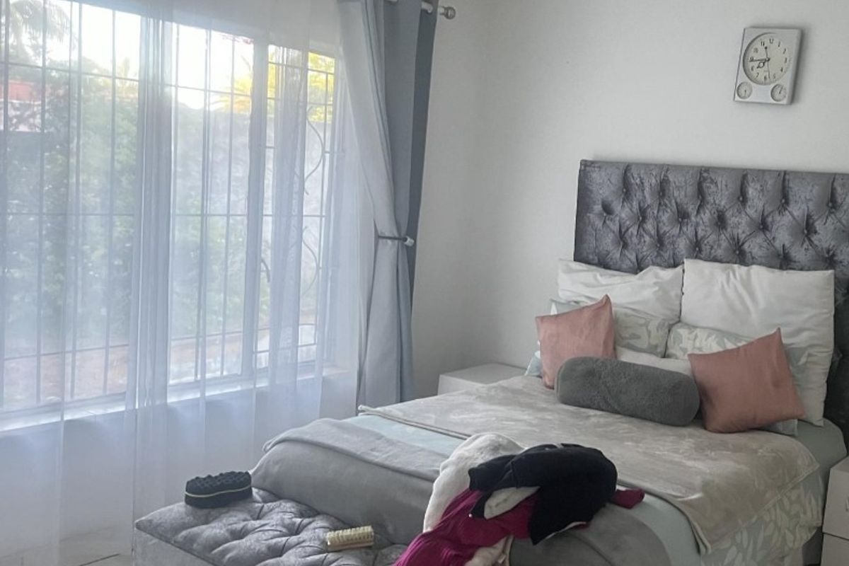 A bedroom featuring tiled flooring and a window fitted with security bars, providing natural light.