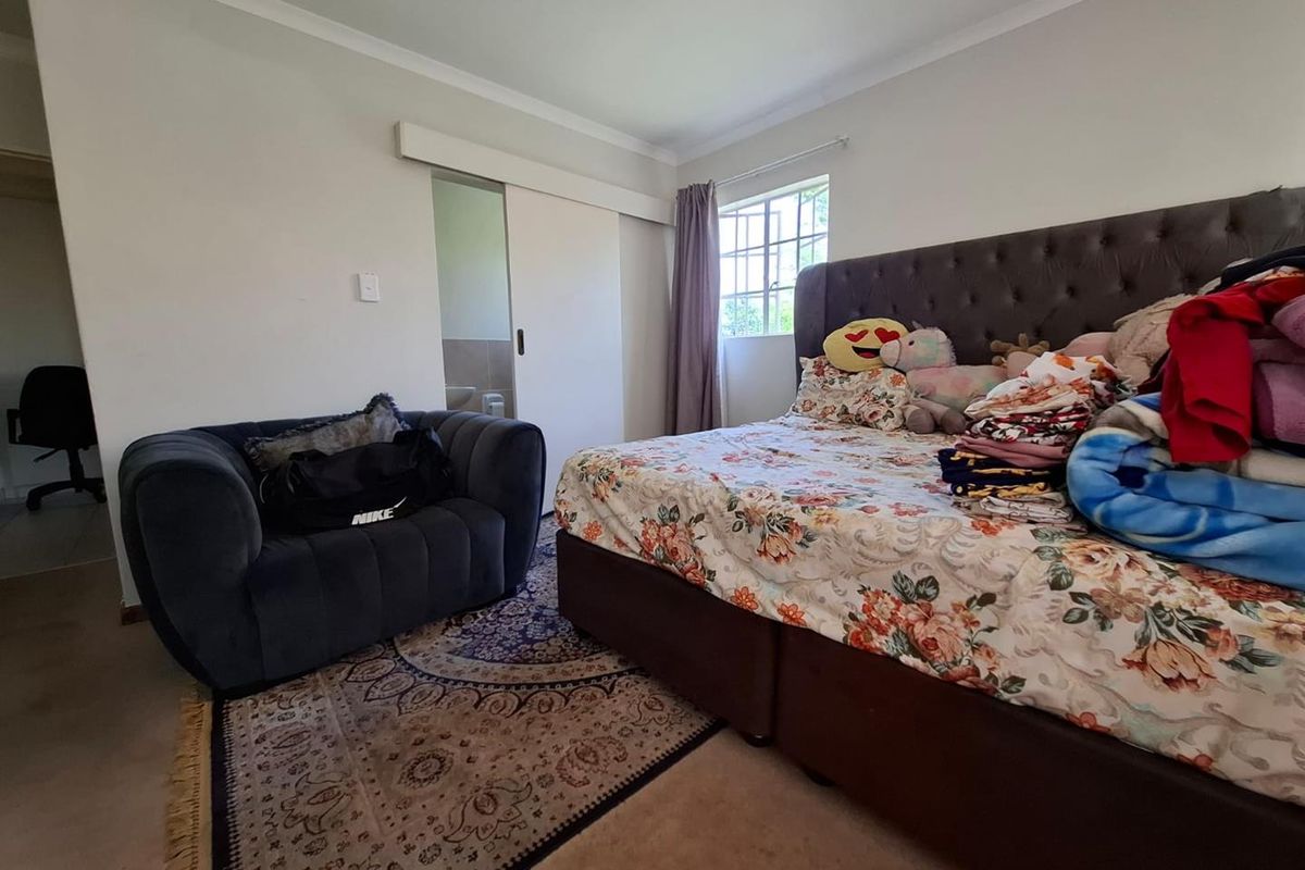 A bedroom featuring a sliding door leading to an en-suite bathroom, a window with natural light, and neutral wall finishes.